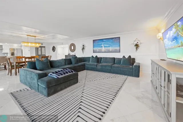 a view of a dining room and livingroom with furniture wooden floor a rug a flat screen tv and a chandelier