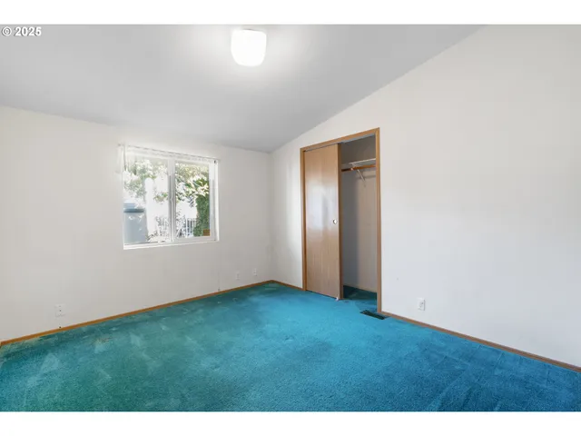 a view of an empty room with closet and window