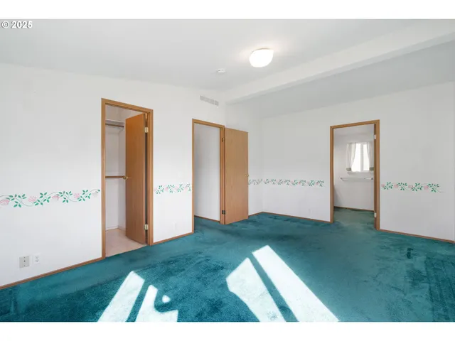 a view of an empty room with closet and windows