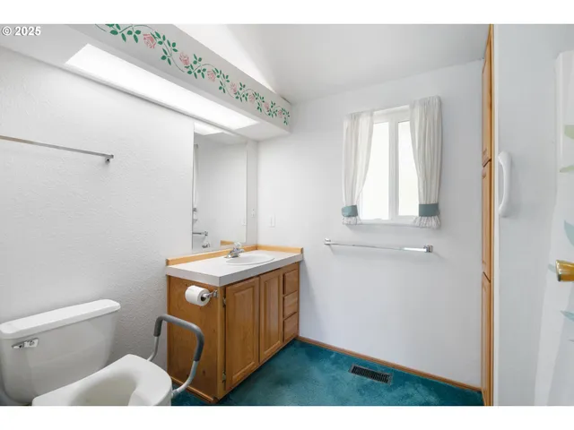 a bathroom with a granite countertop sink and a toilet