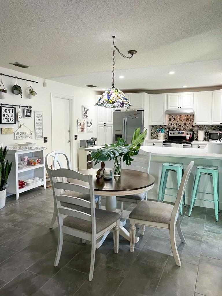 15120 Southwest 141st Place Miami, FL 33186 - Photo 13 of 13 a dining room filled chandelier and kitchen view