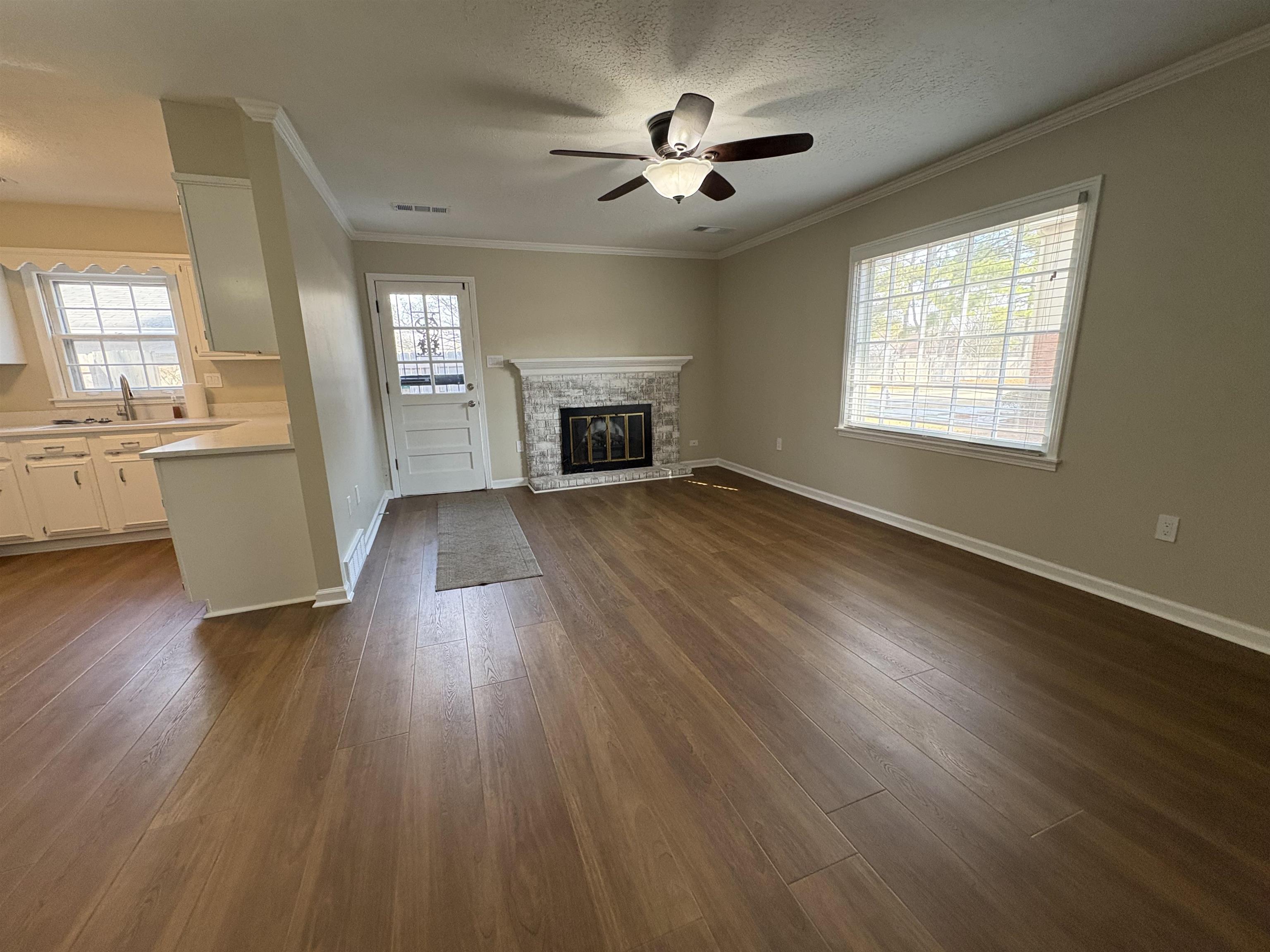 6985 Fords Station Road, Unit 41 Germantown, TN 38138 - Photo 10 of 20 Unfurnished living room featuring dark wood finished floors, crown molding, a ceiling fan, a textured ceiling, and a stone fireplace