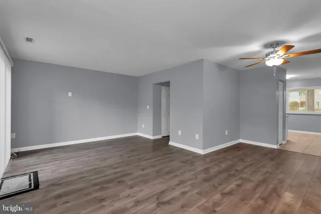 a view of an empty room with window and wooden floor