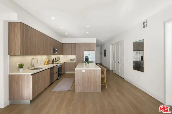 a large white kitchen with stainless steel appliances granite countertop a lot of counter space and wooden floors