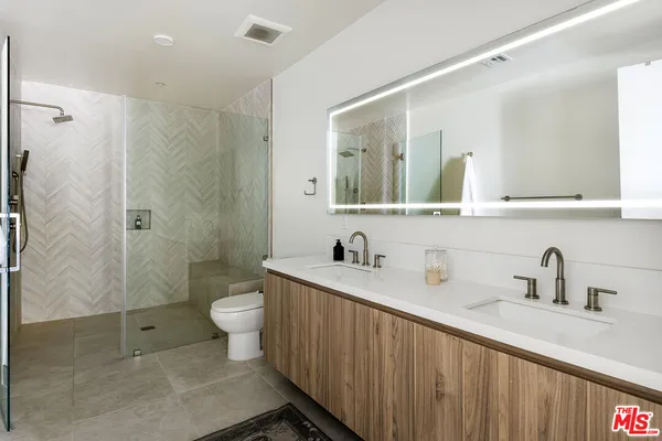 a bathroom with a double vanity sink toilet mirror and shower