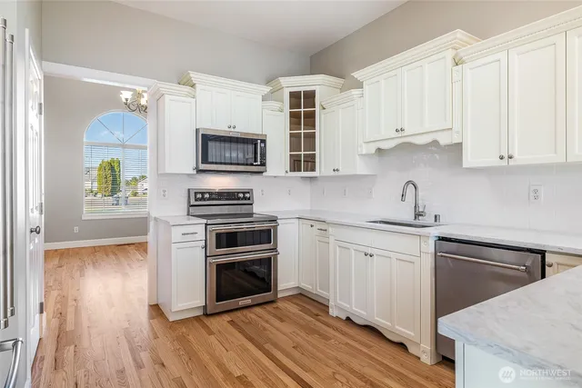 a kitchen with cabinets stainless steel appliances and wooden floor