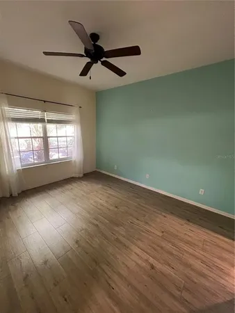 a view of an empty room with wooden floor and a window