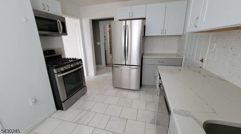 39 Alden Street, Unit 1 Wallington, NJ 07057 - Photo 5 of 6 a kitchen with a refrigerator a stove a microwave and cabinets