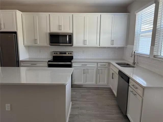 a kitchen with white cabinets and stainless steel appliances