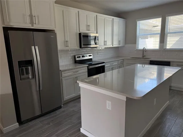 a kitchen with a refrigerator a microwave a sink and cabinets