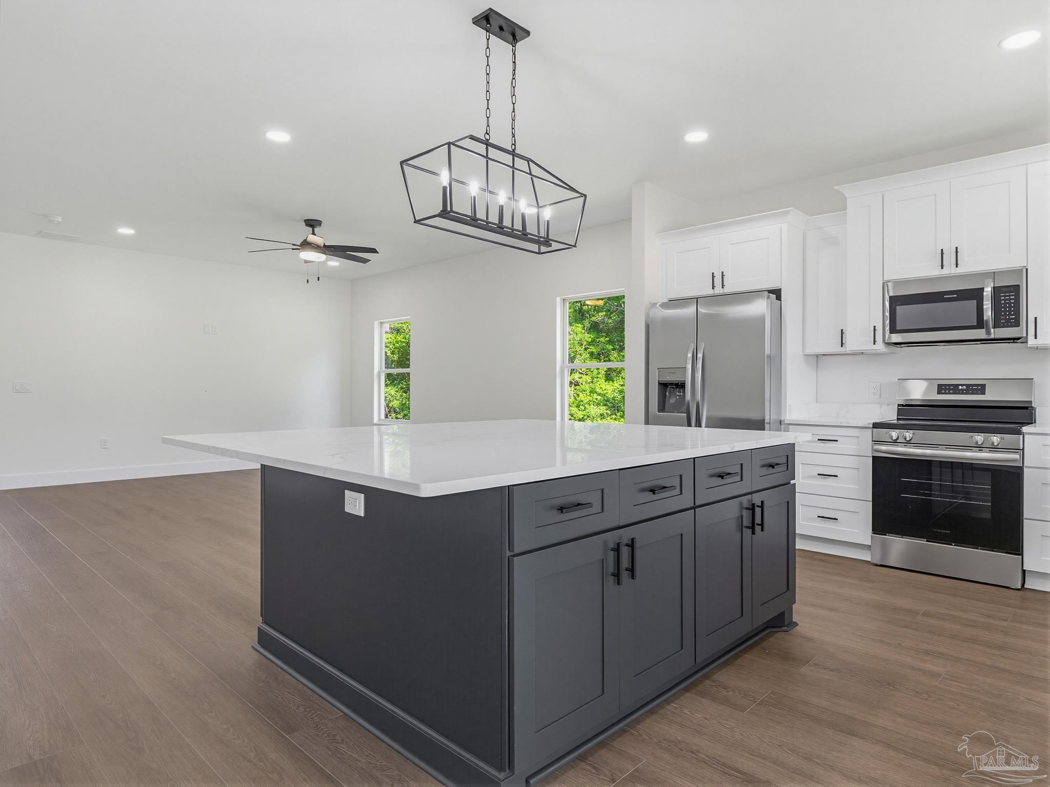 5724 Riviera Drive Milton, FL 32583 - Photo 21 of 52 a kitchen with stainless steel appliances kitchen island granite countertop a refrigerator a stove top oven a sink dishwasher and a refrigerator with wooden floor