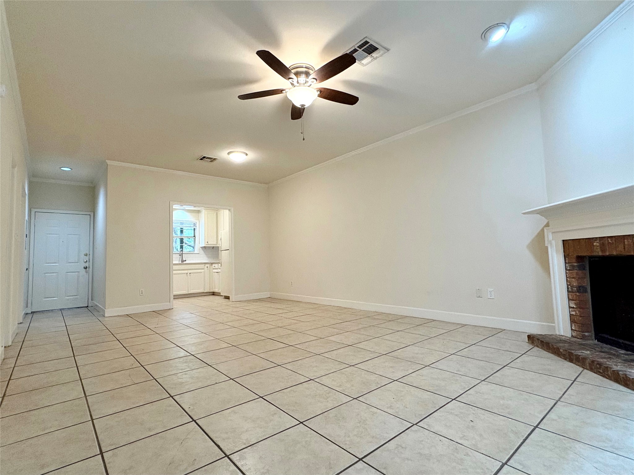 2100 San Gabriel Street, Unit 104 Austin, TX 78705 - Photo 5 of 8 Unfurnished living room with crown molding, light tile patterned floors, ceiling fan, and a brick fireplace