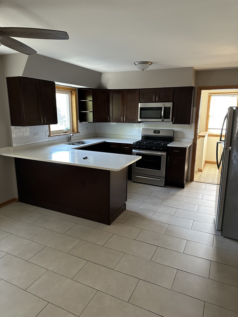 1342 Clinton Avenue Berwyn, IL 60402 - Photo 11 of 16 a large kitchen with stainless steel appliances a stove a sink and a microwave
