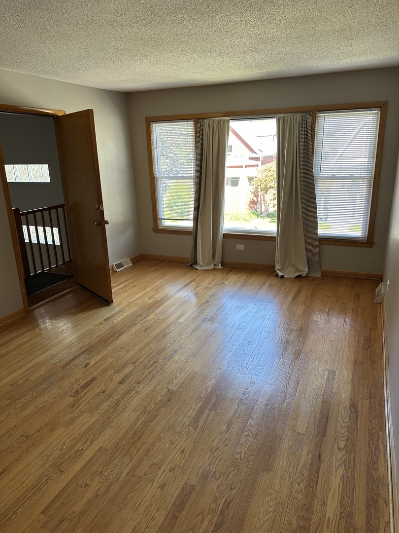 1342 Clinton Avenue Berwyn, IL 60402 - Photo 5 of 16 an empty room with wooden floor and windows
