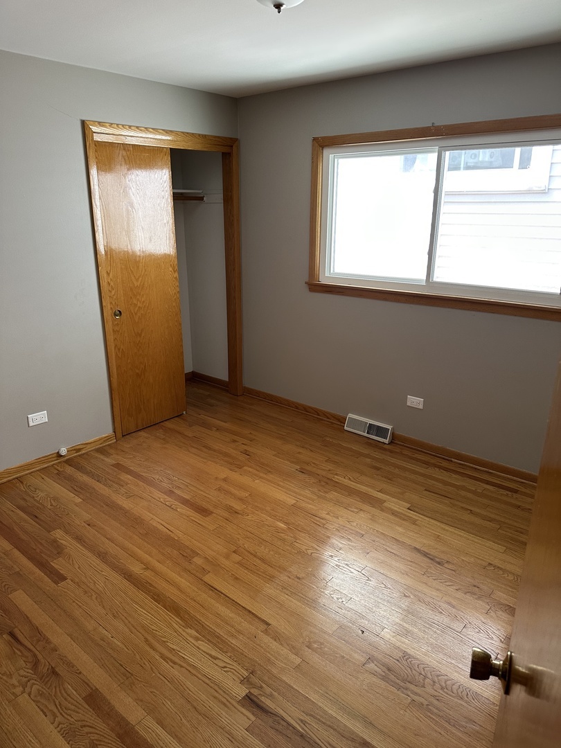 1342 Clinton Avenue Berwyn, IL 60402 - Photo 8 of 16 a view of an empty room with wooden floor and a window