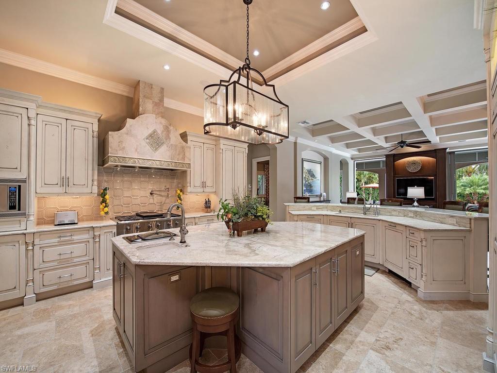 515 Riviera Drive Naples, FL 34103 - Photo 12 of 35 a kitchen with kitchen island granite countertop a sink a counter space appliances and cabinets