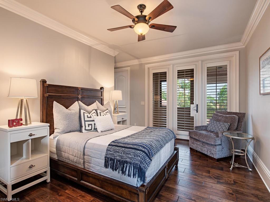 515 Riviera Drive Naples, FL 34103 - Photo 25 of 35 a spacious bedroom with a bed a couch and a chandelier