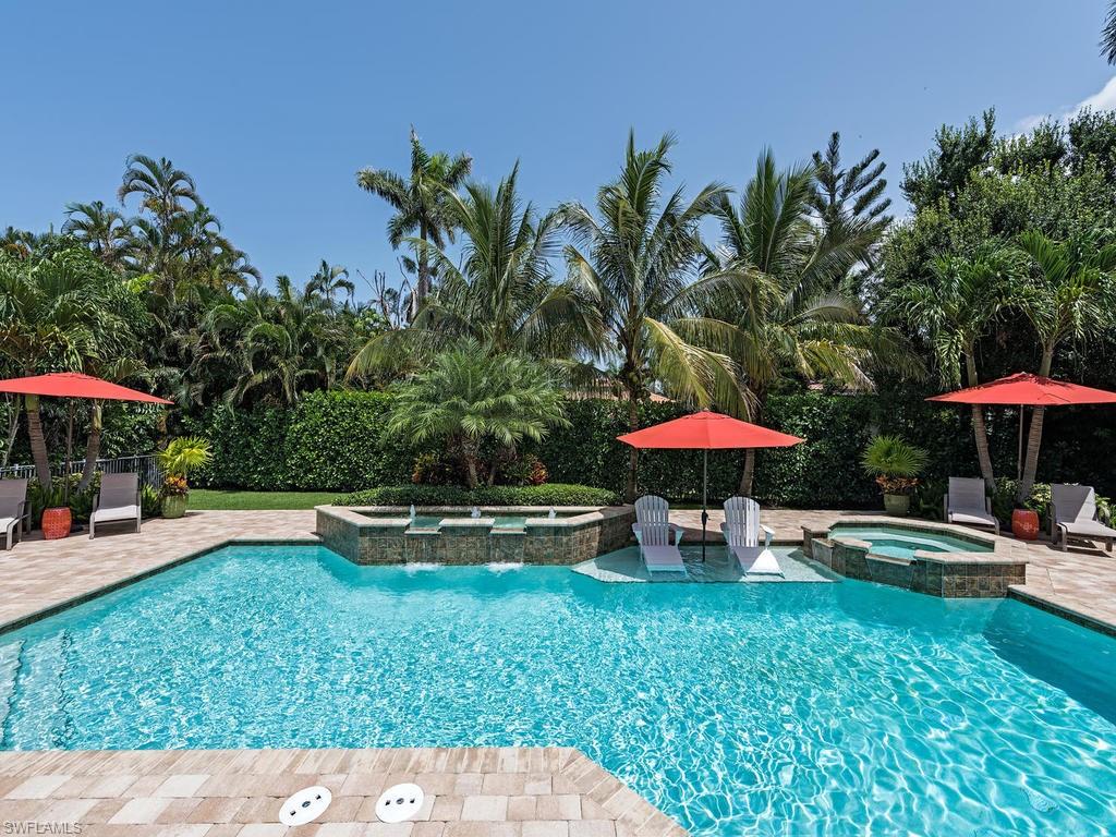 515 Riviera Drive Naples, FL 34103 - Photo 35 of 35 a view of a swimming pool with a table and chairs under an umbrella