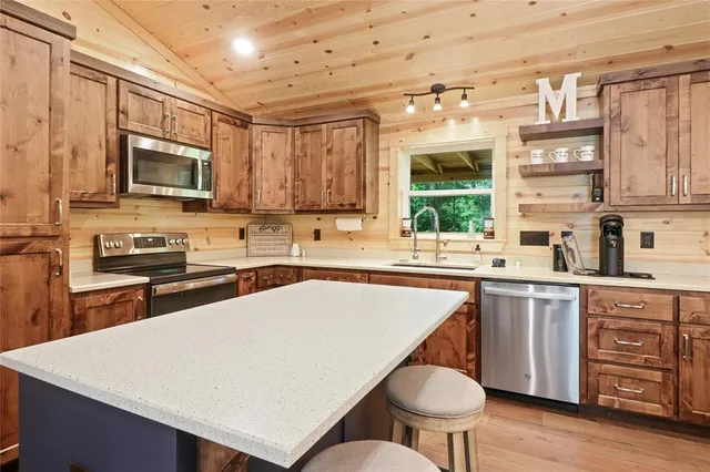 a kitchen with stainless steel appliances granite countertop a stove a sink dishwasher and a microwave oven with wooden cabinets
