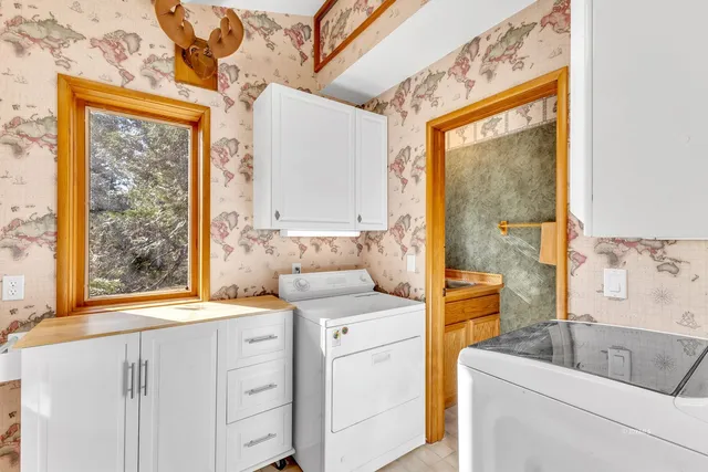 a utility room with stainless steel appliances granite countertop a sink and a window