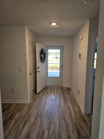a view of hallway with window and wooden floor
