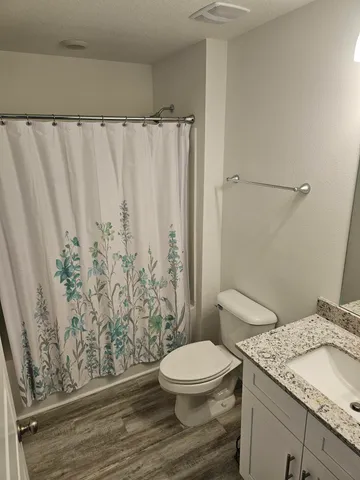 a bathroom with a granite countertop toilet a sink and a shower
