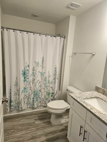 a bathroom with a granite countertop sink and a toilet