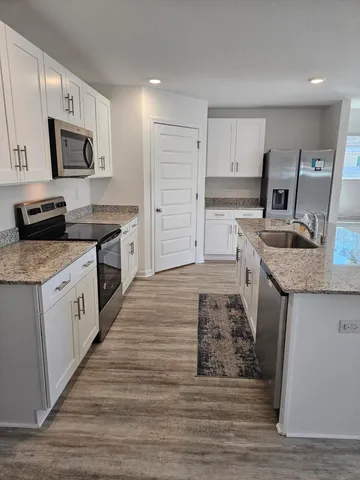 a kitchen with stainless steel appliances granite countertop a sink stove microwave and refrigerator