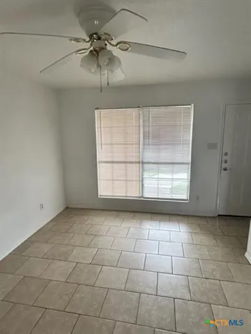 an empty room with windows and fan
