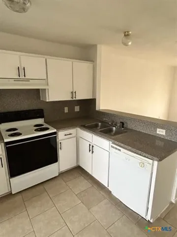 a white kitchen with granite top and stainless steel appliances