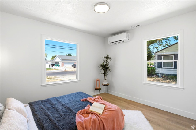 307 Flint Street Layton, UT 84041 - Photo 9 of 13 Bright interior space featuring two large windows with white trim, wood-finish flooring, a wall-mounted mini-split system, and a flush-mount ceiling light