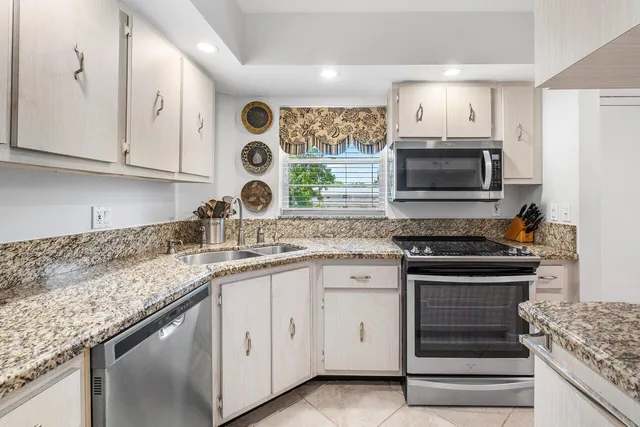a kitchen with granite countertop white cabinets and window