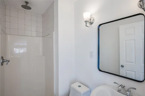 a bathroom with a shower a mirror and a sink