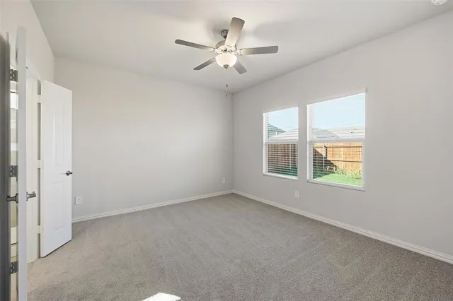 an empty room with a window and a ceiling fan