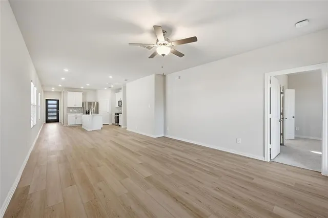 a view of a livingroom with a ceiling fan wooden floor and a ceiling fan
