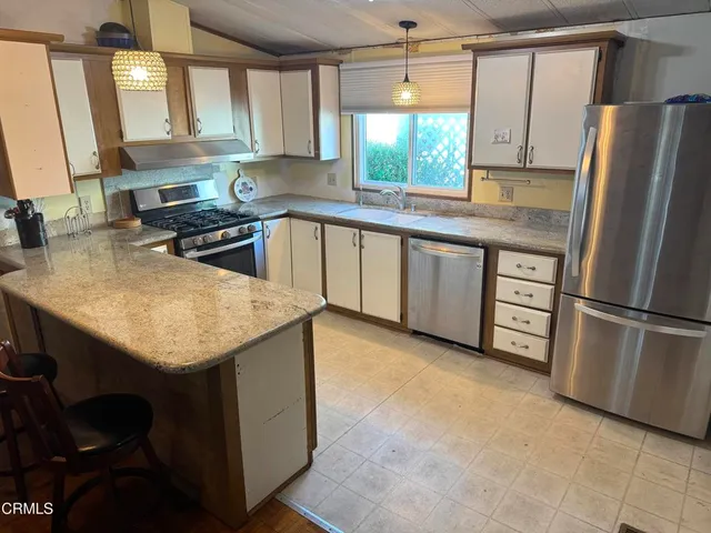 a kitchen with stainless steel appliances granite countertop a sink window and cabinets
