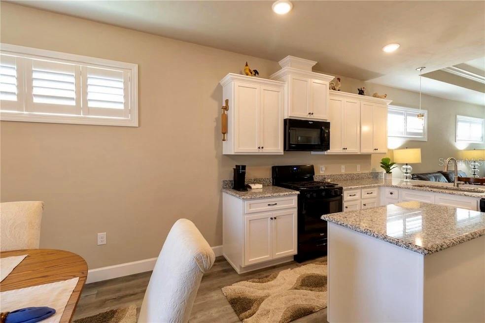 24650 Southwest 17th Place Newberry, FL 32669 - Photo 11 of 19 a kitchen with granite countertop a sink and a stove top oven with wooden floor