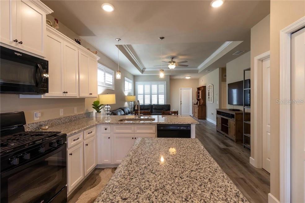 24650 Southwest 17th Place Newberry, FL 32669 - Photo 12 of 19 a kitchen with stainless steel appliances granite countertop a stove top oven a sink a dining table and chairs with wooden floor
