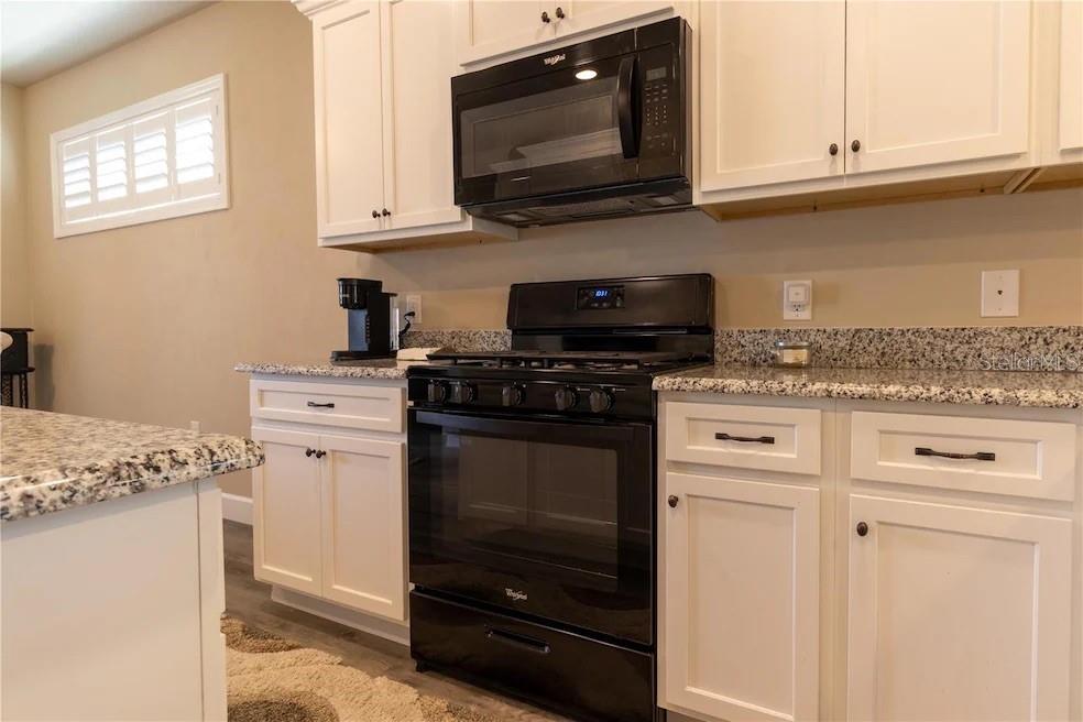 24650 Southwest 17th Place Newberry, FL 32669 - Photo 13 of 19 a kitchen with granite countertop cabinets stainless steel appliances and wooden floor