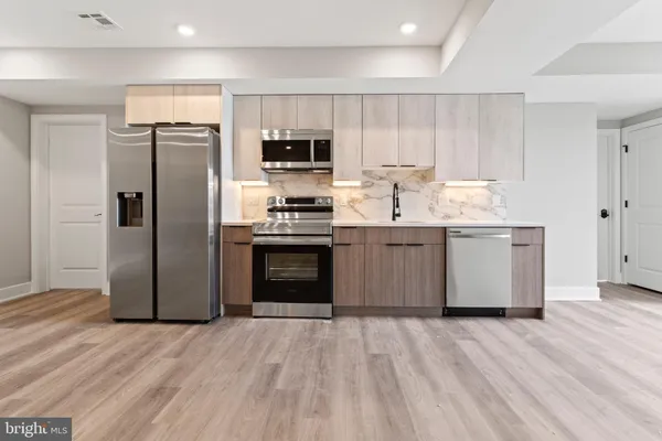 a kitchen with stainless steel appliances kitchen island granite countertop a refrigerator stove and sink