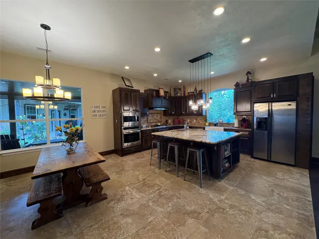 a kitchen with kitchen island a counter top space a sink stainless steel appliances and cabinets