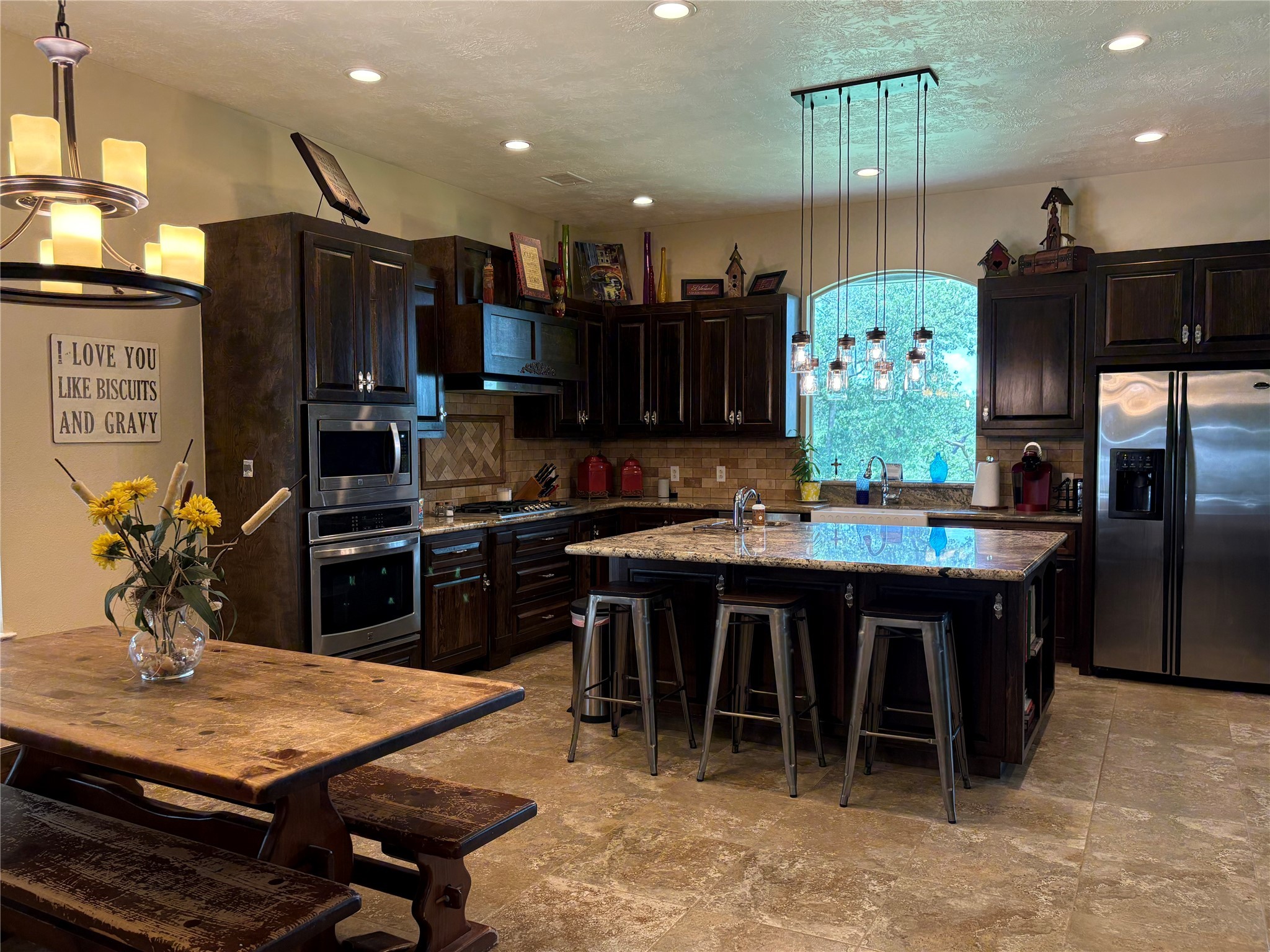 8595 Jared Road Bellville, TX 77418 - Photo 10 of 30 a kitchen with stainless steel appliances kitchen island granite countertop a table chairs and a refrigerator