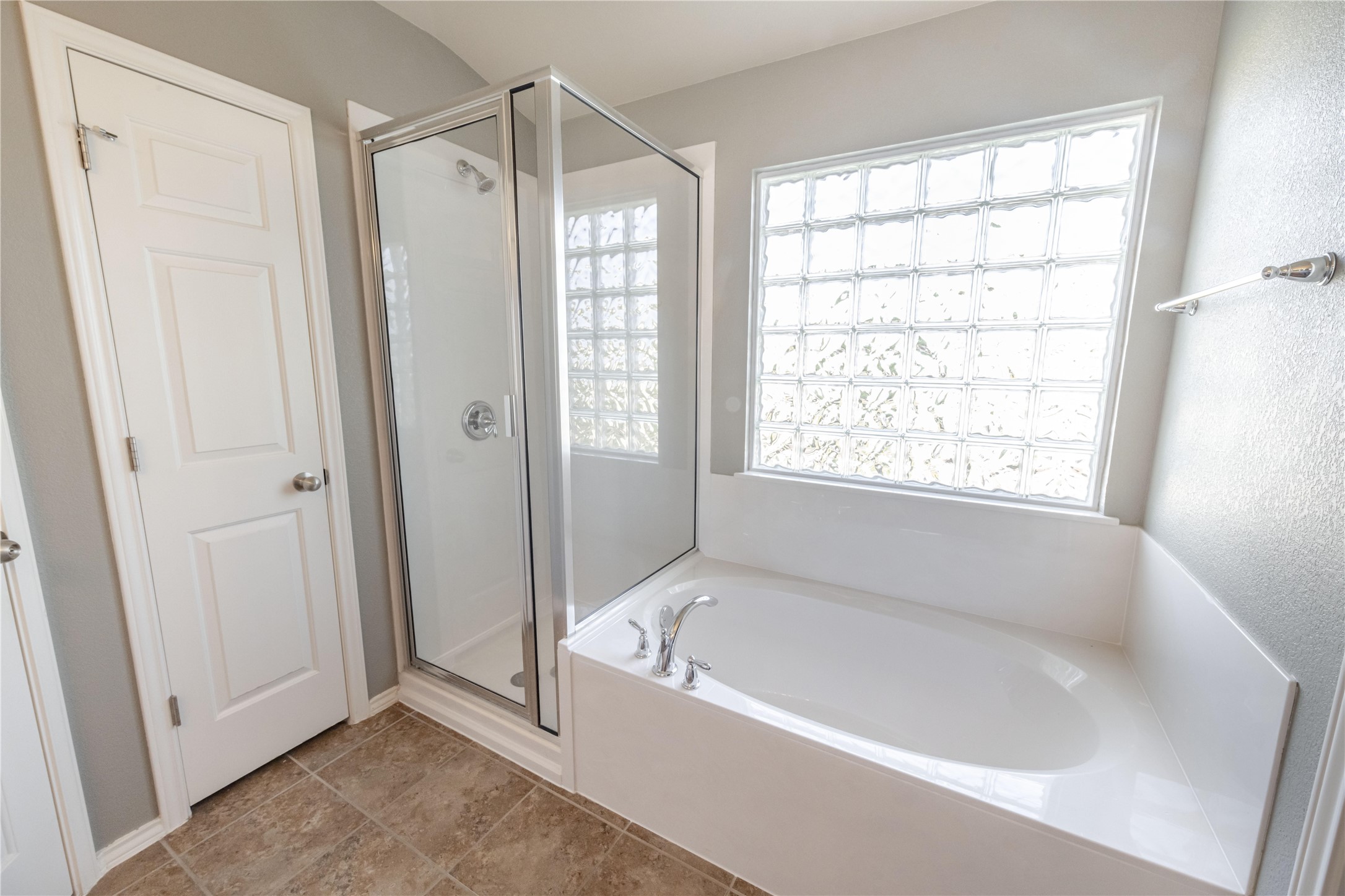 11221 Old Quarry Road Austin, TX 78717 - Photo 12 of 19 A glass-enclosed shower stands adjacent to a soaking tub beneath a privacy glass block window.