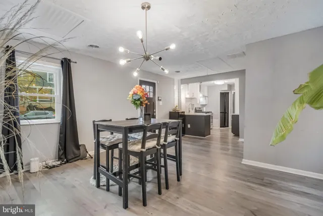 a view of a dining room and livingroom with furniture wooden floor a chandelier