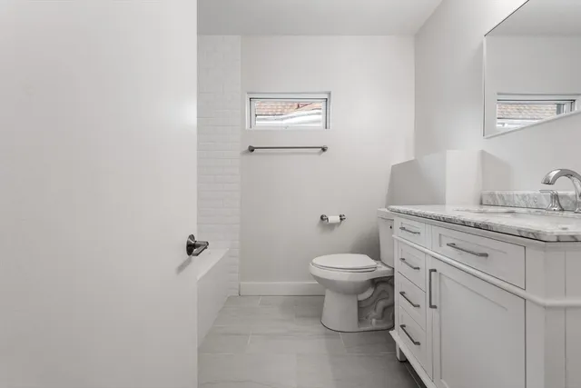 a bathroom with a granite countertop toilet and sink