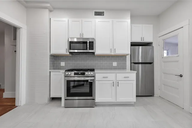 a kitchen with stainless steel appliances granite countertop a stove a refrigerator and a microwave