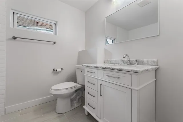 a bathroom with a granite countertop toilet sink and mirror