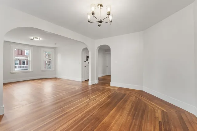 a view of an empty room with a window and wooden floor