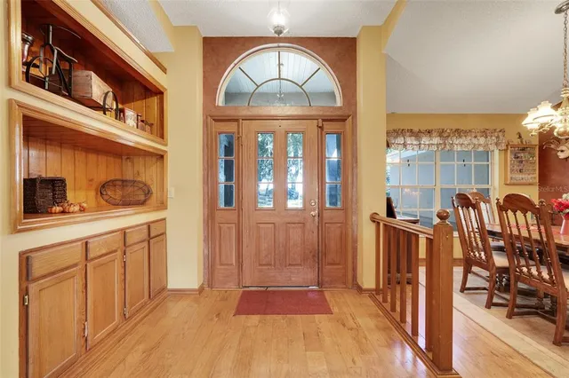 a view of a dining room with furniture a chandelier and large windows