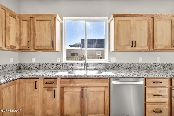 a kitchen with granite countertop a sink window and cabinets